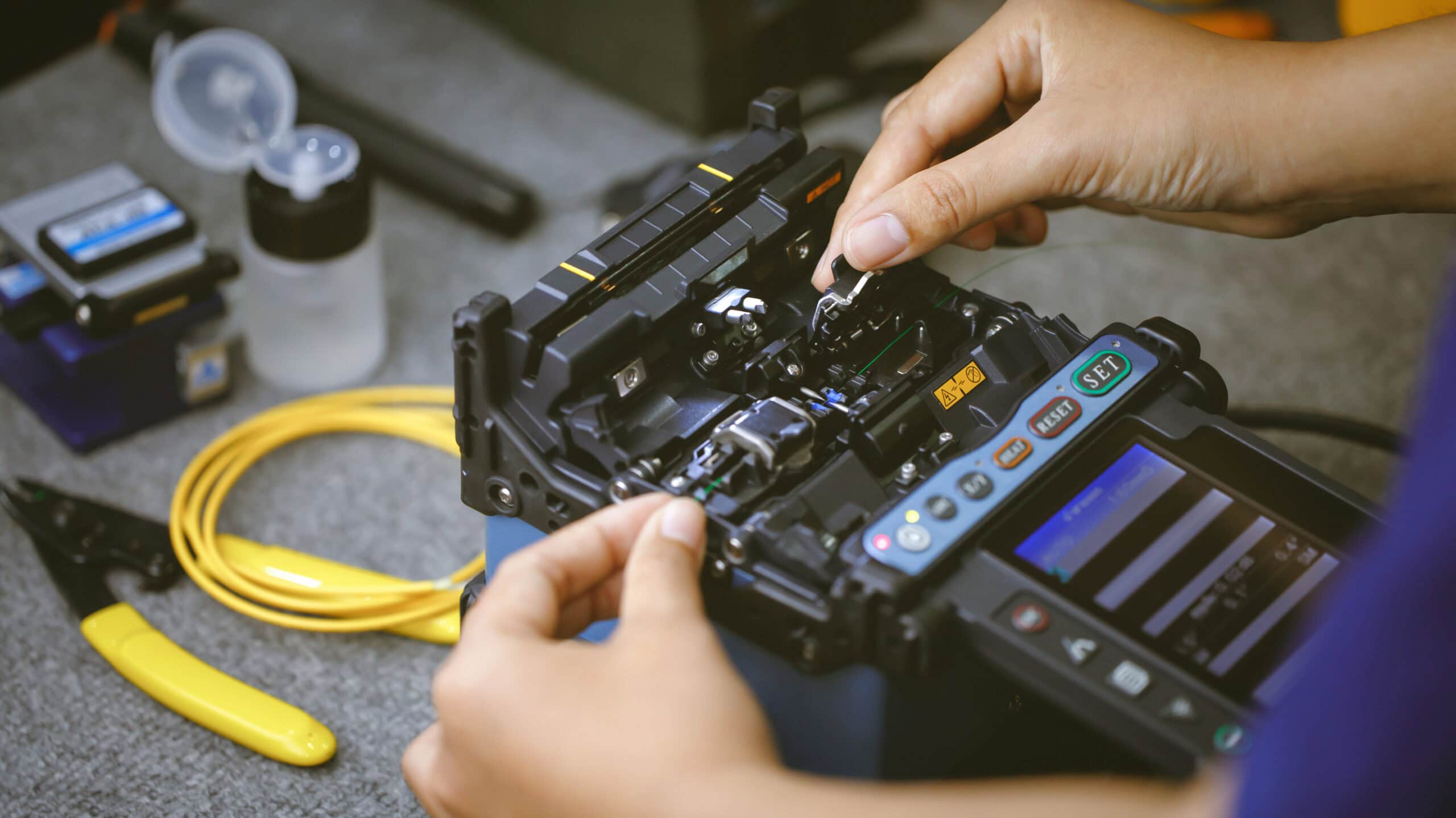 Fiberoptic Fusion Splicing Technician , Internet cable connection, fiber optic fusion splicing machine. Concept of fiber optic connection by skilled technicians.